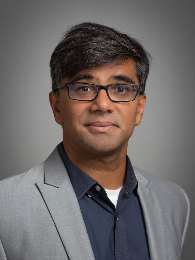 A portrait of a person in front of a grey studio background.